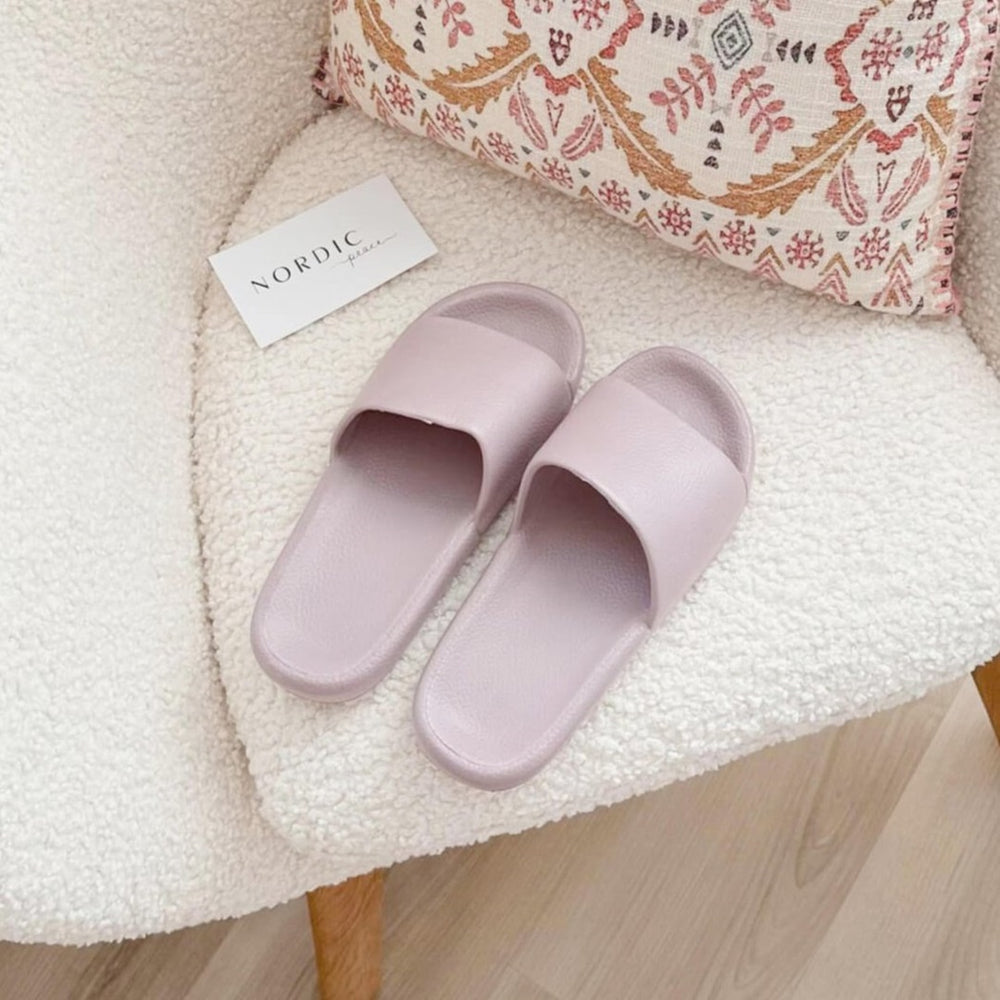 Purple slide sandals on a white chair.