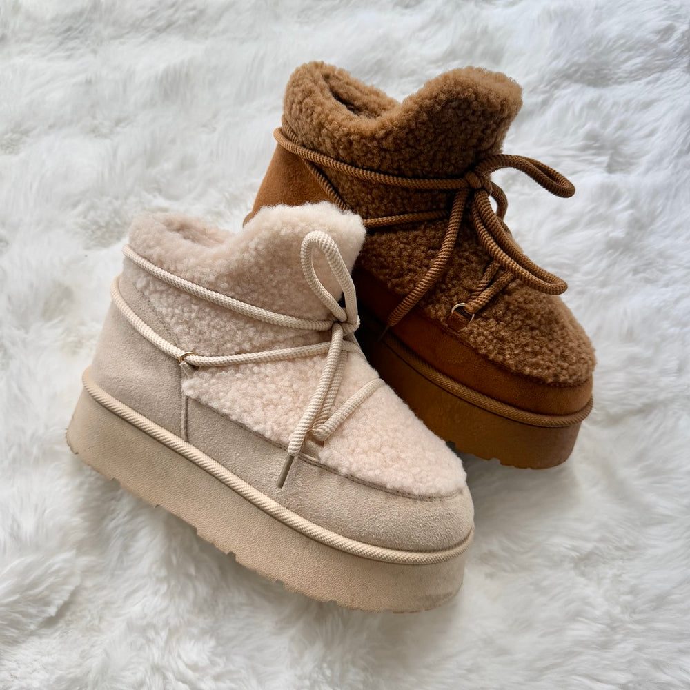 Two fuzzy winter boots on a white surface.
