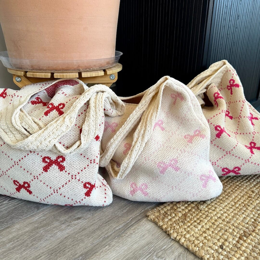 Three cream tote bags with pink bows.