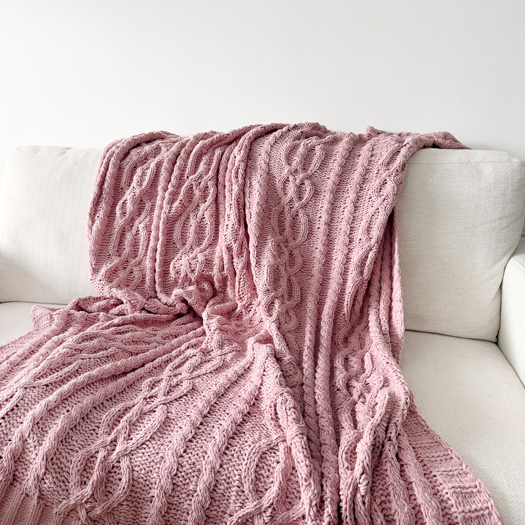 Pink throw blanket with textured knit pattern and ribbed edges