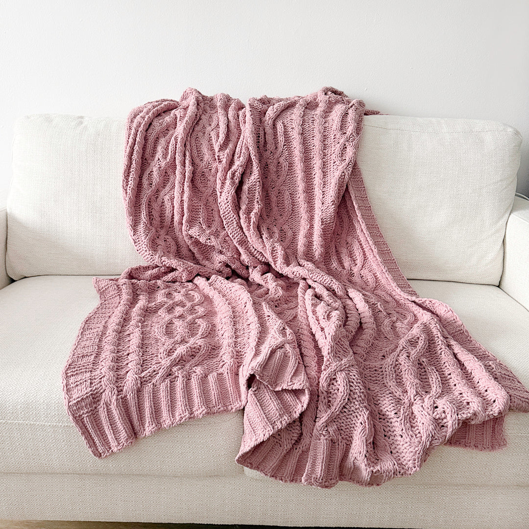 Pink cable knit throw blanket with chunky woven texture