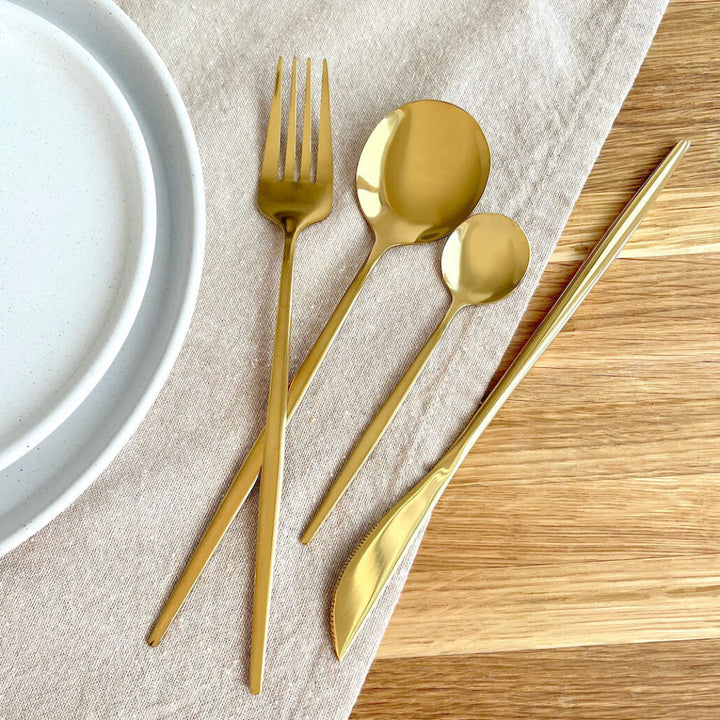 Gold flatware with plates on a linen cloth
