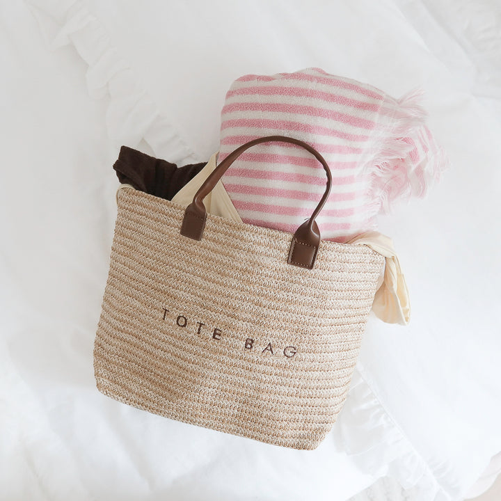 Neutral straw tote bag with brown faux leather handles