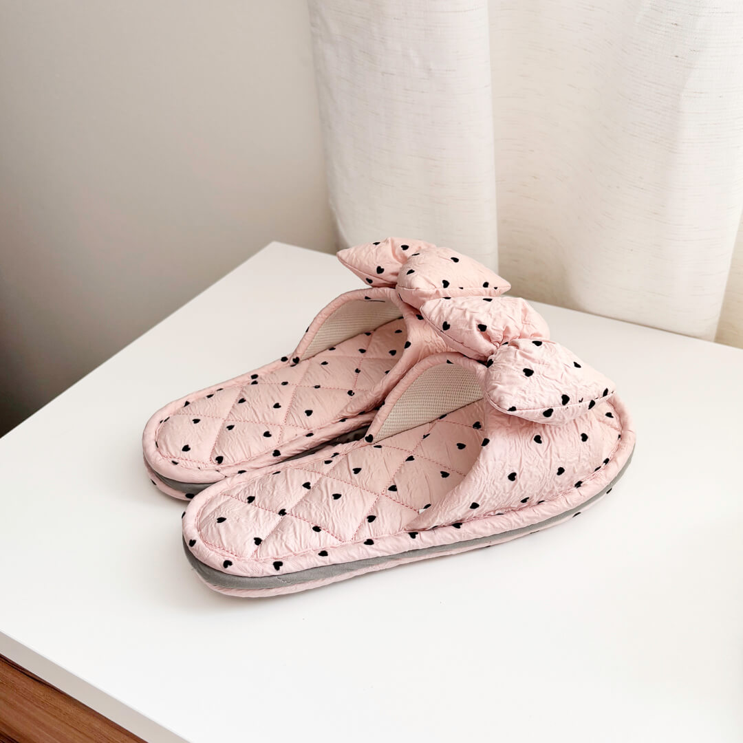 pink slippers with black heart pattern and bow