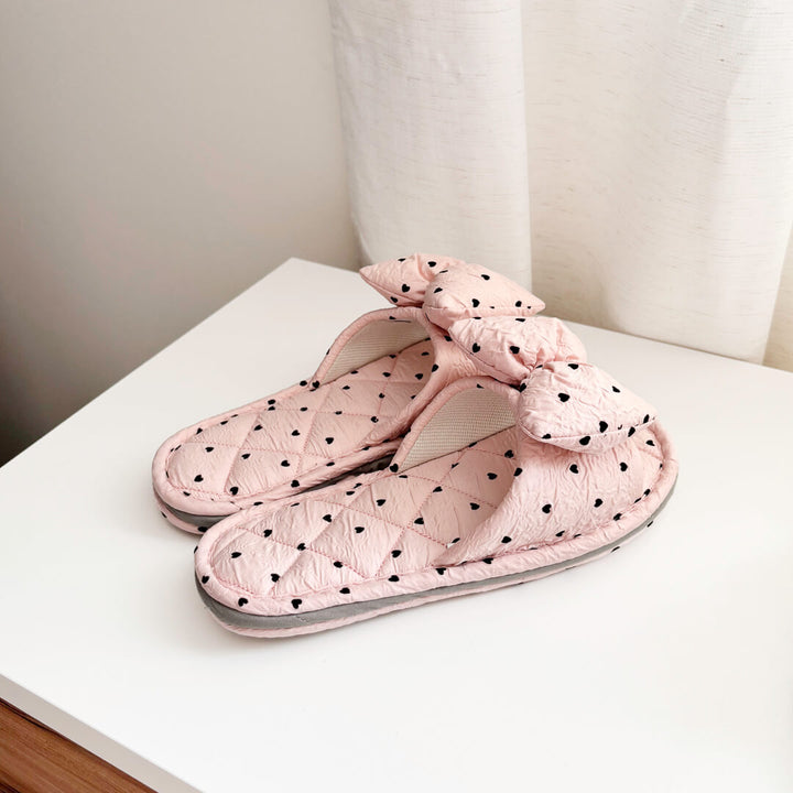 pink slippers with black heart pattern and bow
