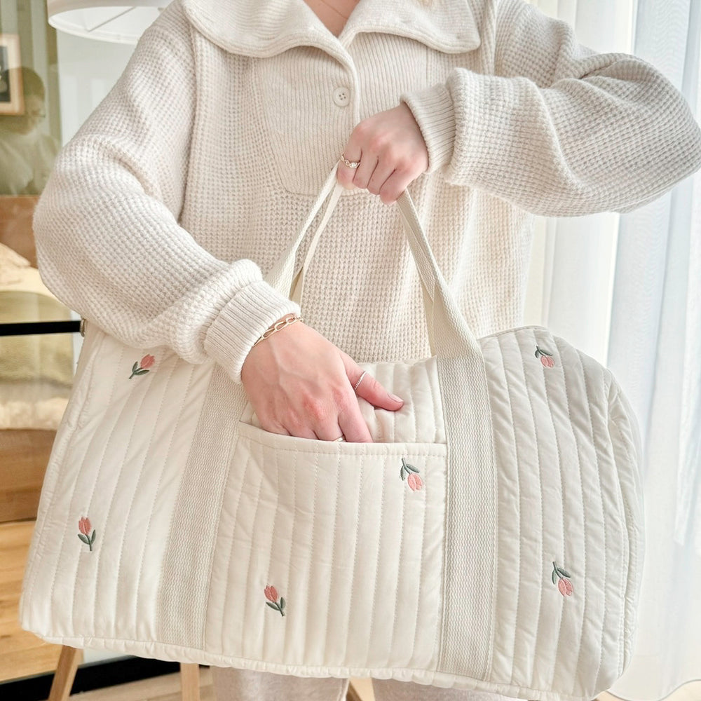 Woman holding a quilted tote bag with floral embroidery