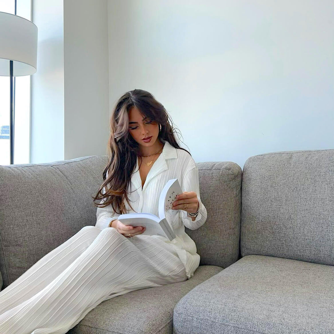 Woman in white outfit reading on a couch