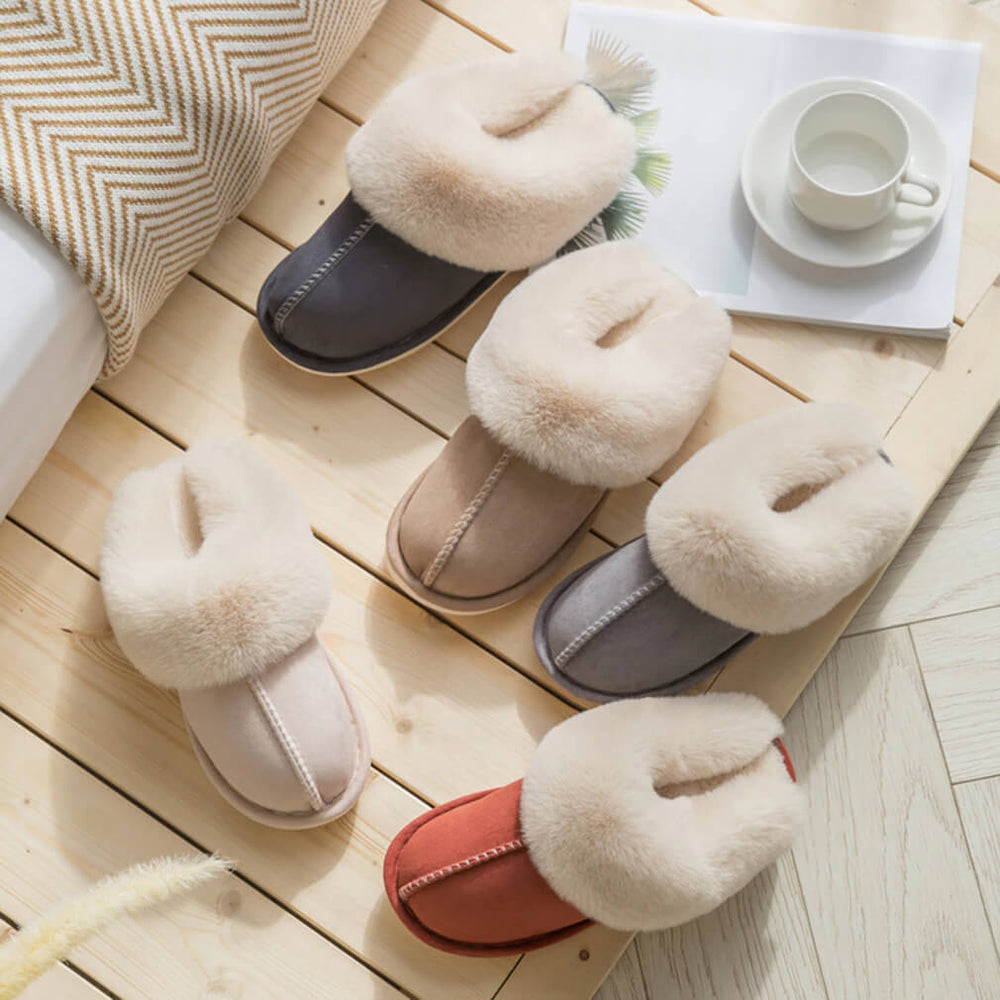 Five pairs of fluffy slippers on a wooden surface.