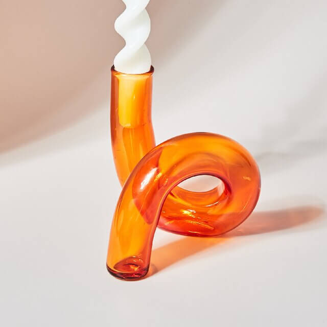 Orange glass candlestick with white candle